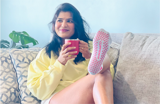 Woman relaxing on a couch while wearing Copper Fit Gripper Socks product