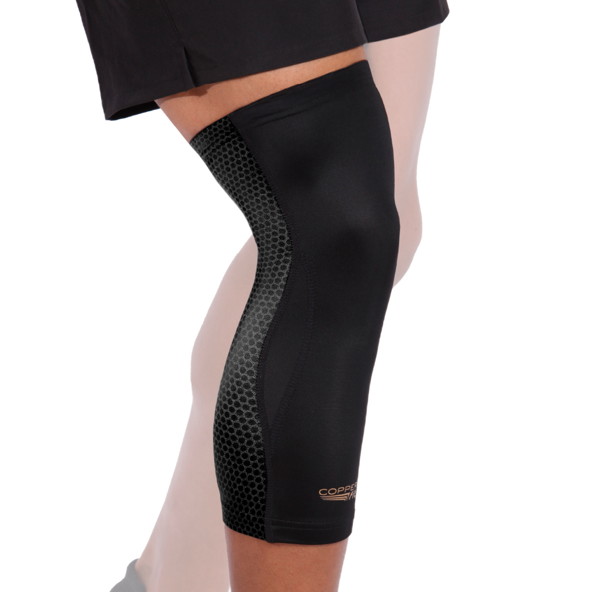 A person wearing a black knee compression sleeve with a honeycomb pattern on the side.